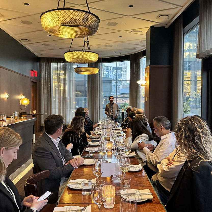 The private dining room at Ci Siamo, a long table set beneath woven chandeliers