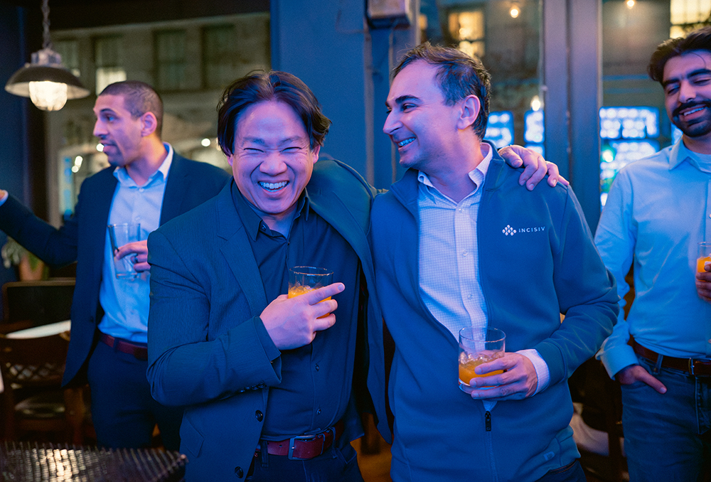 Guests laughing over drinks at Incisiv’s Happy Hour